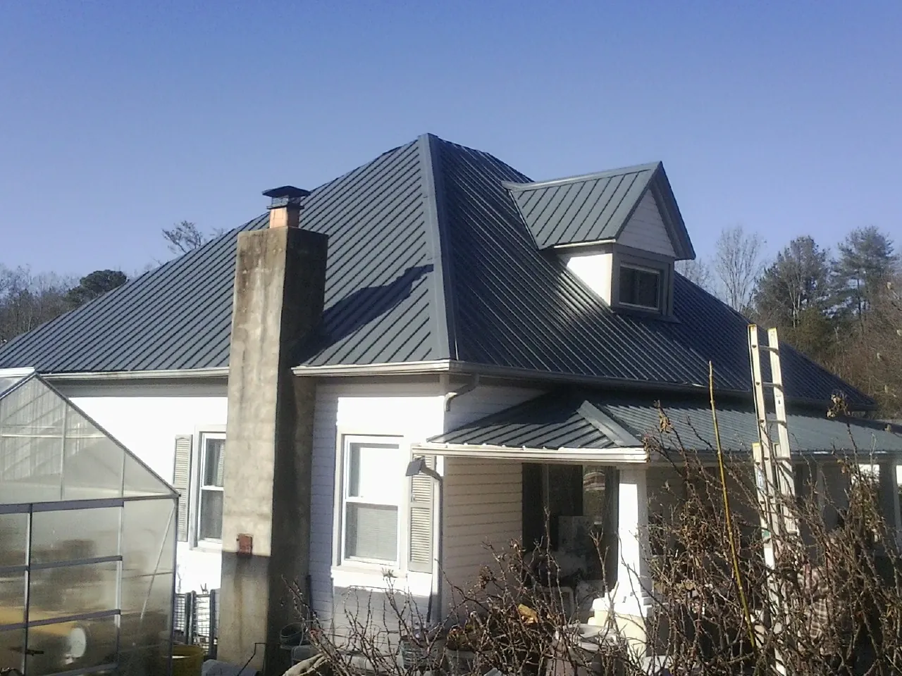 Dark blue standing seam metal roof on a white farmhouse with dormer — Slate & Tile Roof Repair by Roofing Brothers in Hauppauge