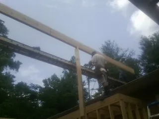 Carpenter setting a ridge beam over a new addition frame — Ice Dam Removal by Roofing Brothers in Hauppauge