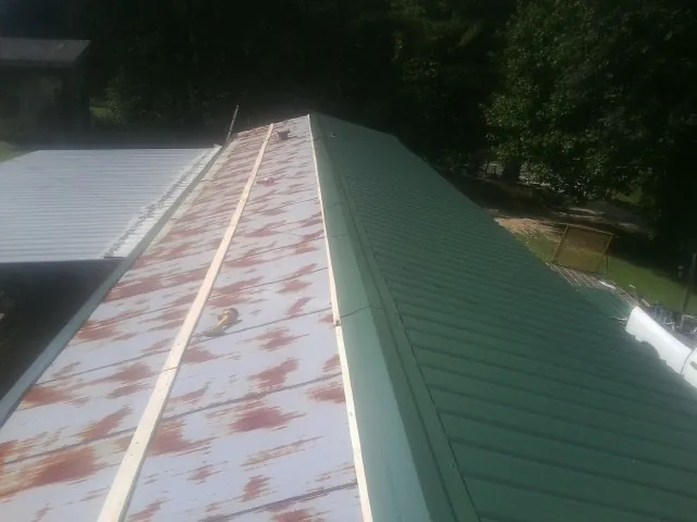 Old rusted panels beside newly installed green metal roofing — Wind Damage Roof Repair by Roofing Brothers in Hauppauge