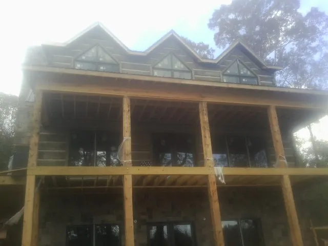 Dormers and porch framing on a large log home under construction — Roof Coating work by our crew in Hauppauge
