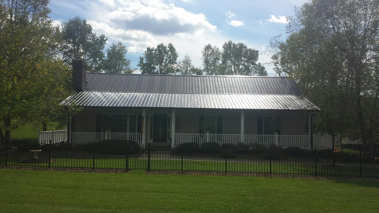 Gray metal roof on a brick ranch with a full width front porch — Gutter Guard Installation work by our crew in Hauppauge