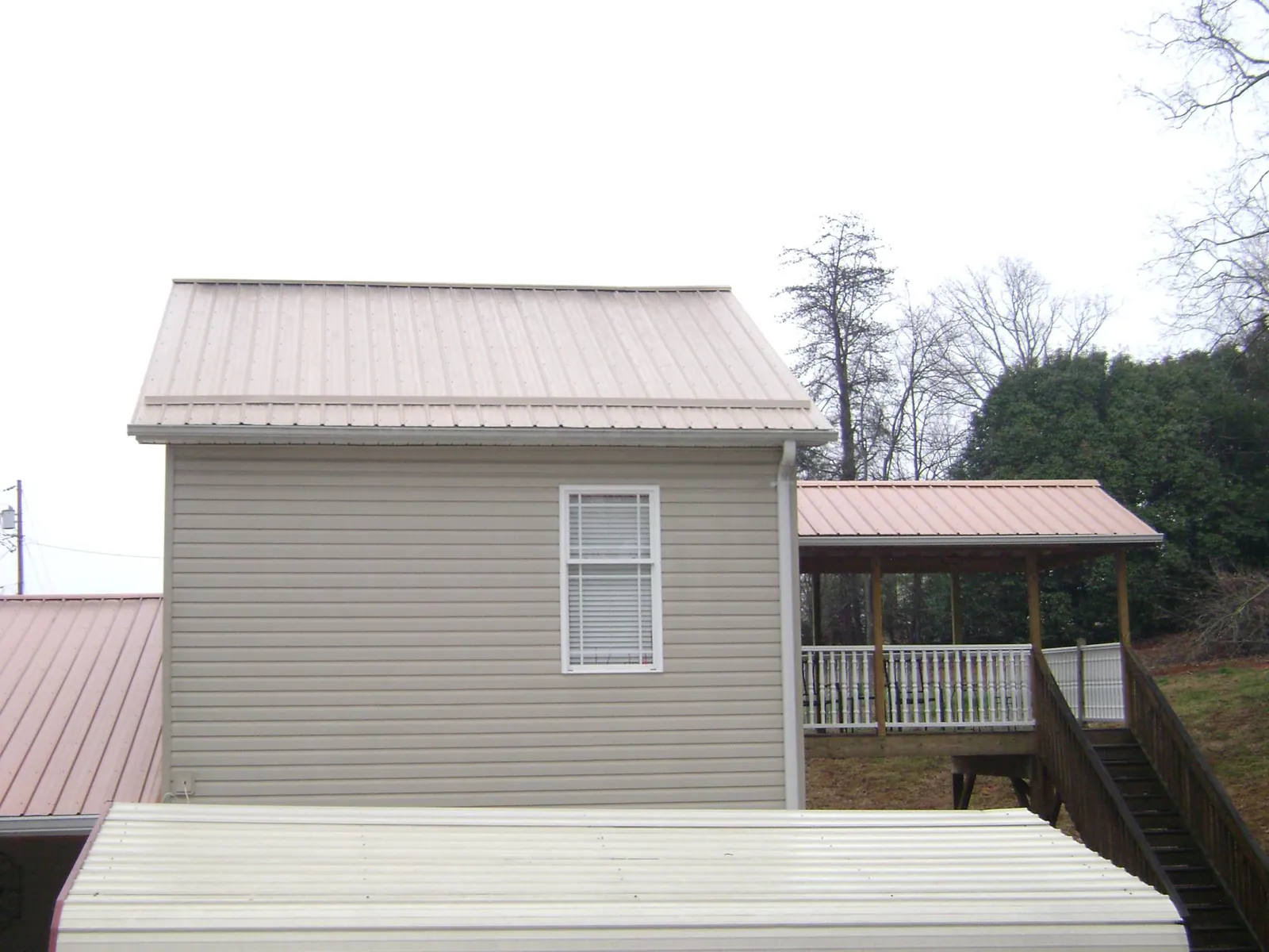 Tan metal roofs on a two story addition and attached porch, from a Roof Replacement job in Hauppauge