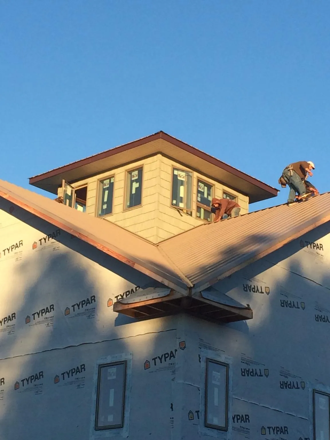 Roofers working around a rooftop cupola on a new metal roof at sunset — Roof Waterproofing in Hauppauge by Roofing Brothers